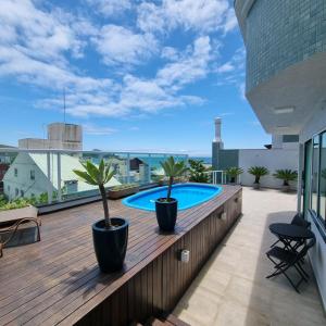 una terraza con 2 macetas y una piscina en Cobertura com Piscina 50 mt do Mar, en Bombinhas