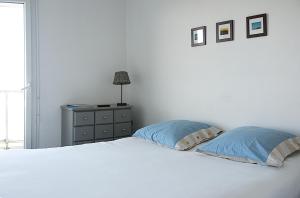 een slaapkamer met een wit bed met 2 kussens en een dressoir bij LE BORD de MER in Calais