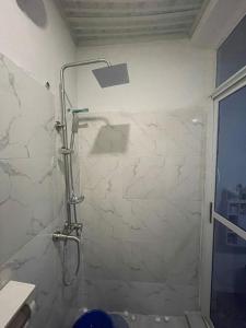 y baño con ducha y pared de piedra blanca. en Scandinavian style Duplex Gowon Estate Egbeda, en Lagos