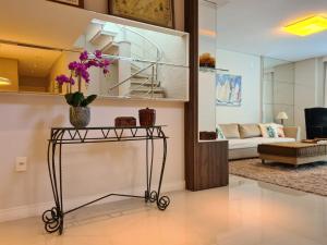 una sala de estar con una mesa con flores púrpuras. en Cobertura com Piscina 50 mt do Mar, en Bombinhas