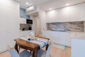 Ariston & Casinò - Appartamento con Giardino e Garage في سانريمو: مطبخ مع طاولة خشبية ودواليب بيضاء