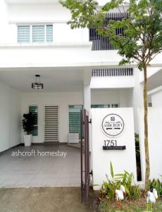 une maison blanche avec un panneau devant elle dans l'établissement Ashcroft homestay, à Kota Bharu