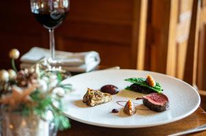 a plate of food on a table with a glass of wine at Holbeck Ghyll Country House Hotel with Stunning Lake Views in Windermere +16 photos