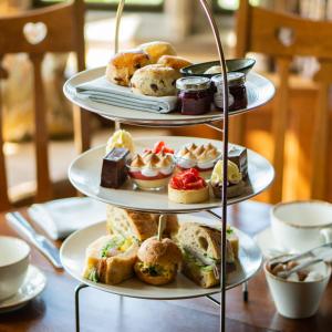 a three tiered display of pastries and desserts on a table at Holbeck Ghyll Country House Hotel with Stunning Lake Views in Windermere