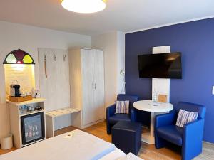 a room with blue chairs and a table and a tv at Hotel Garni Dünennest in Sankt Peter-Ording