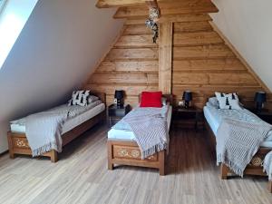 a attic room with two beds and a wooden wall at Willa Wschód Słońca in Bukowina Tatrzańska