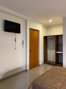 um quarto com uma cama e uma televisão na parede em Hotel Alba em Ica