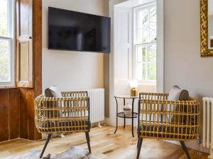 a living room with two chairs and a tv on the wall at Riverside Cottage in Blair Atholl