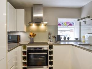 a kitchen with white cabinets and a stove top oven at Riverside Cottage in Blair Atholl