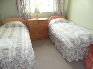 a bedroom with two beds and a dresser and a window at Bungalow in lovely setting.Ten minutes to Longleat in North Bradley
