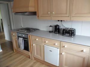 a kitchen with wooden cabinets and a stove top oven at Bungalow in lovely setting.Ten minutes to Longleat in North Bradley