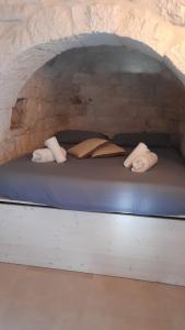 a bed in a stone wall with pillows and towels at Trullo Scrascia. in Ceglie Messapica