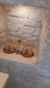 a shelf with four tea pots and bowls on it at Trullo Scrascia. in Ceglie Messapica