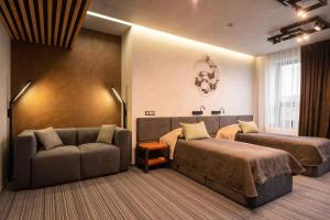 ein Hotelzimmer mit zwei Betten und einer Couch in der Unterkunft MOJO HALL Hotel in Luzk