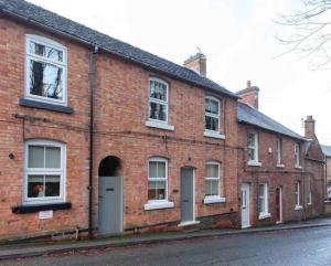 a red brick building with white windows on a street at Cosy Heather Cottage in Ashbourne