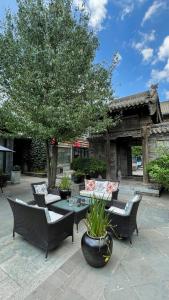 un patio con sillas, una mesa y un árbol en Datong Yunzhong Traditional Courtyard, en Datong