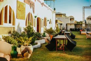 un patio con macetas, mesa y bancos en Lake House by Tunisia Green Resort, en Qaryat at Ta‘mīr as Siyāḩīyah