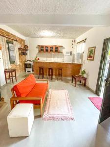 sala de estar con sofá naranja y cocina en Casa Pau Brasil, en Prado