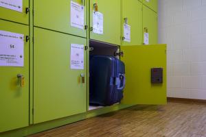 a room with green lockers with a suitcase in it at Chalet Hostel @ Backpackers Villa Interlaken in Interlaken