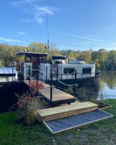 un barco está atracado junto a un muelle de madera en Studio sur la péniche Santa Julia à Chantilly Insolys, en Saint-Leu-dʼEsserent