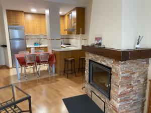 uma sala de estar com lareira de pedra e uma cozinha em Precioso apartamento en zona residencial em Panticosa