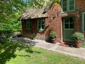 uma casa de tijolos com uma porta verde e janelas em Kruemelkate em Witzwort