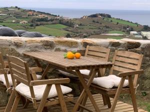 una mesa de madera y sillas con naranjas. en Golindo Goikoa en Getaria