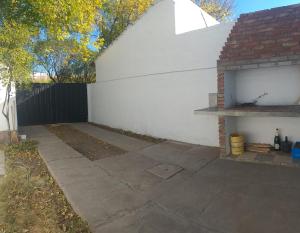 un patio trasero con una pared blanca y un patio en Casa Alojamiento San Rafael en San Rafael