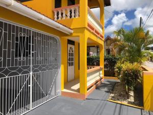 a yellow house with a gate in front of it at DonaMae 2 story Barbados House in Bridgetown