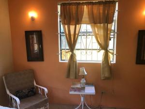 um quarto com uma janela, uma cadeira e uma mesa em DonaMae 2 story Barbados House em Bridgetown