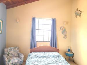 a bedroom with a bed and a window and a chair at DonaMae 2 story Barbados House in Bridgetown