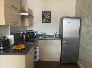 a kitchen with a stainless steel refrigerator and a sink at Lovely 1 Bedroom Apartment in Plymouth