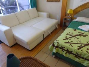a living room with a white couch and a bed at Fare Arearea Sweet Studio in Papeete