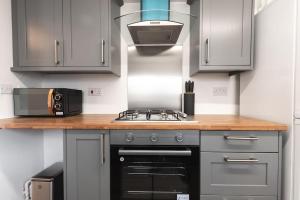 a kitchen with a stove and a microwave at Beautiful 4 bedroom house in Reading