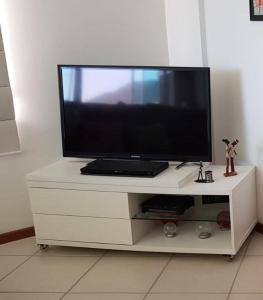 TV de pantalla plana en un centro de entretenimiento blanco en Residencial Ilha Verde (101), en Florianópolis