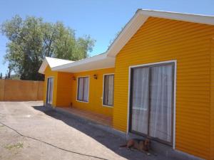 a dog laying in front of a yellow house at Granja Vip Valle de Elqui in Vicuña