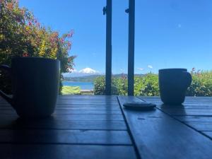 dos tazas sentadas en una mesa con vistas al océano en Volcano & Lake Family Hostel, en Villarrica