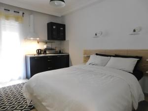 a bedroom with a white bed and a kitchen at Brand New Studio 1 in Komotini
