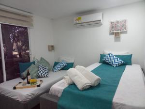a bedroom with two beds with blue and white pillows at CABAÑA EN ISLA FRENTE A CARTAGENA in Cartagena de Indias