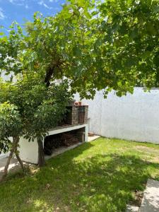 un banco sentado junto a una pared blanca con un árbol en CASA LAS PARRAS en San Rafael