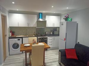 a kitchen with a table and a refrigerator at Brand New Cosy Apartment 3 Sleep, Garden access Free Wi-Fi & Parking in Newport