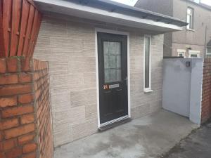 a house with a black door and a brick wall at Newport rental property Furnished studio near train station Free Wifi Parking in Newport