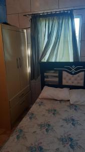 a bedroom with a bed with a dresser and a window at Pousada da Amália in Cidreira +11 photos