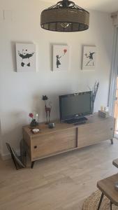 a living room with a television on a wooden cabinet at acogedor apartamento 2 dormitorios in Granada