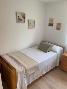 um quarto branco com uma cama e duas fotografias na parede em acogedor apartamento 2 dormitorios em Granada