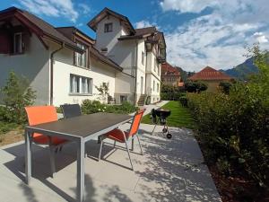 um pátio com uma mesa e cadeiras em frente a uma casa em Henry's Apartments Interlaken em Interlaken