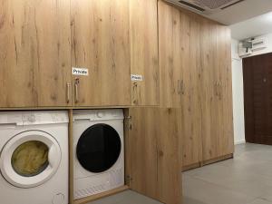 lavadero con lavadora y armarios de madera en Ideal Apartment n4, en Pristina
