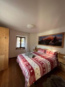 een slaapkamer met een bed met een rode en witte deken bij DOLOMITI HOUSE STUBE in Fiera di Primiero