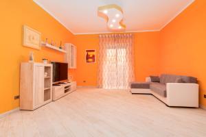 a living room with orange walls and a couch and a television at Il Ciclamino in Tarquinia