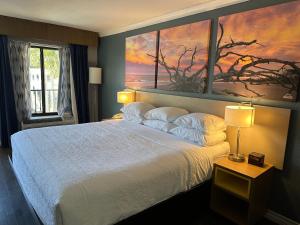 1 dormitorio con 1 cama grande y una pintura en la pared en Days Inn by Wyndham Pensacola - Historic Downtown, en Pensacola